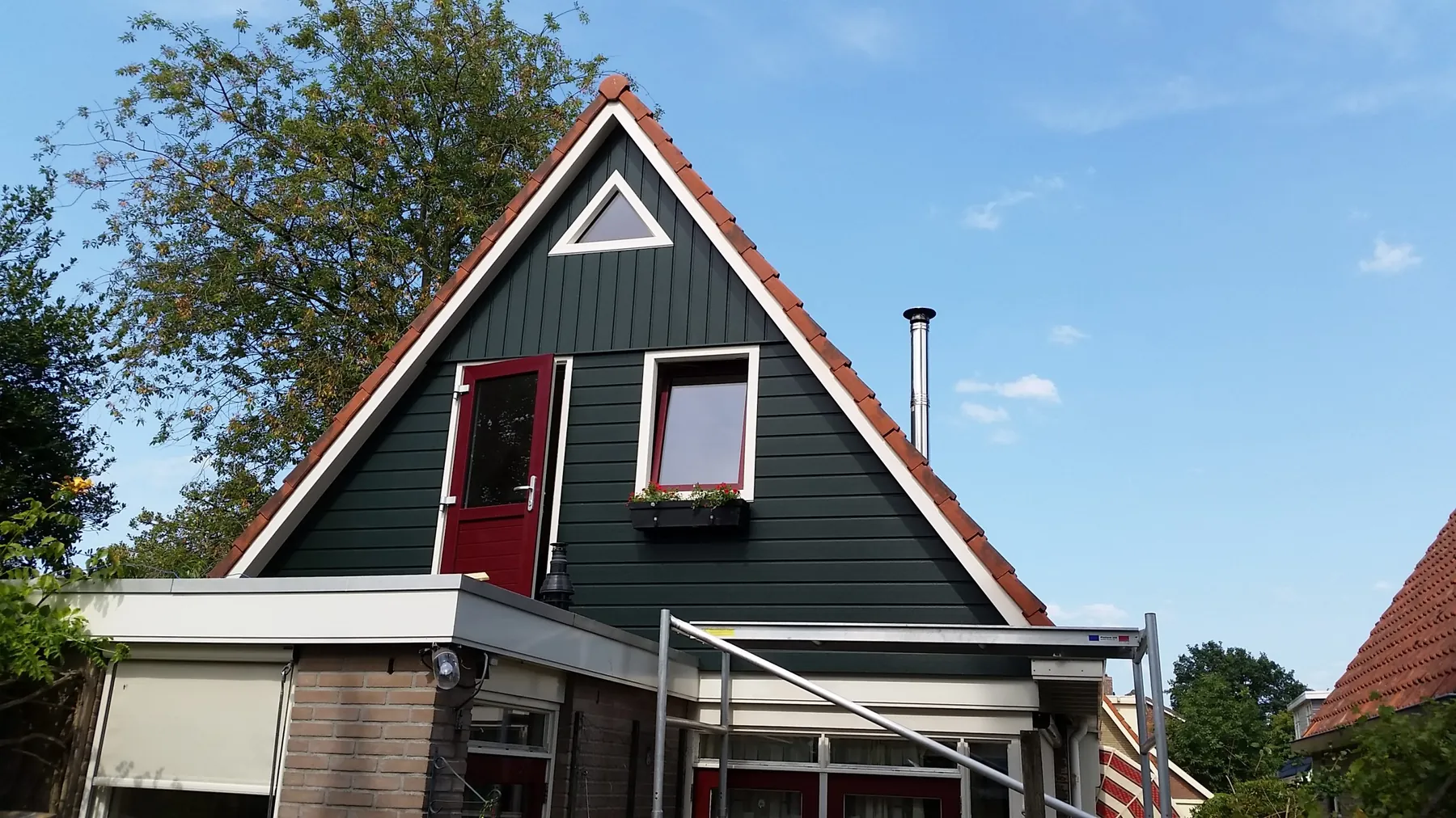 Woning in Heerenveen met een door Van Leersum gebouwde uitbreiding van de eerste
 verdieping, met donkergroene gevelbekleding en een rode deur